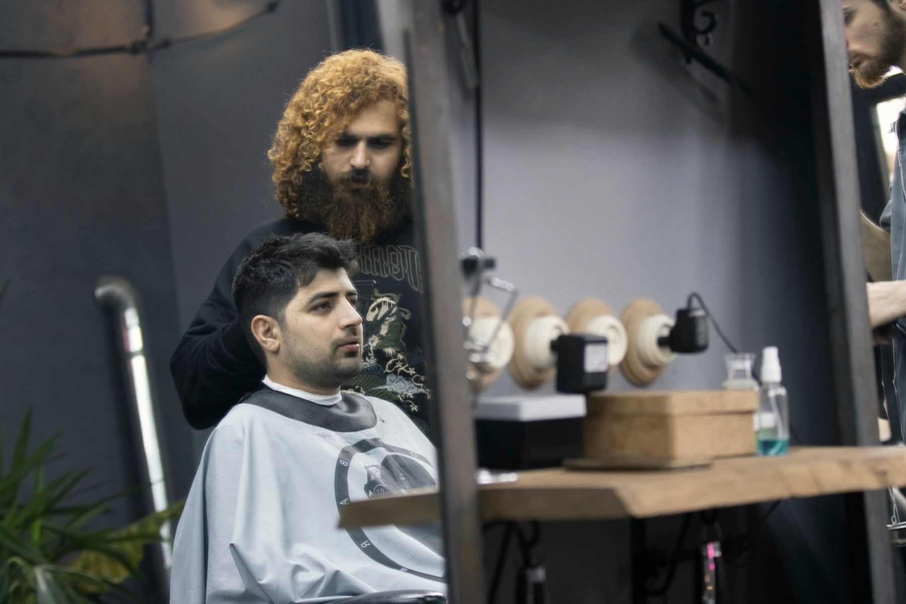 Kapper knipt een klant in een moderne salon met spiegels en planken
