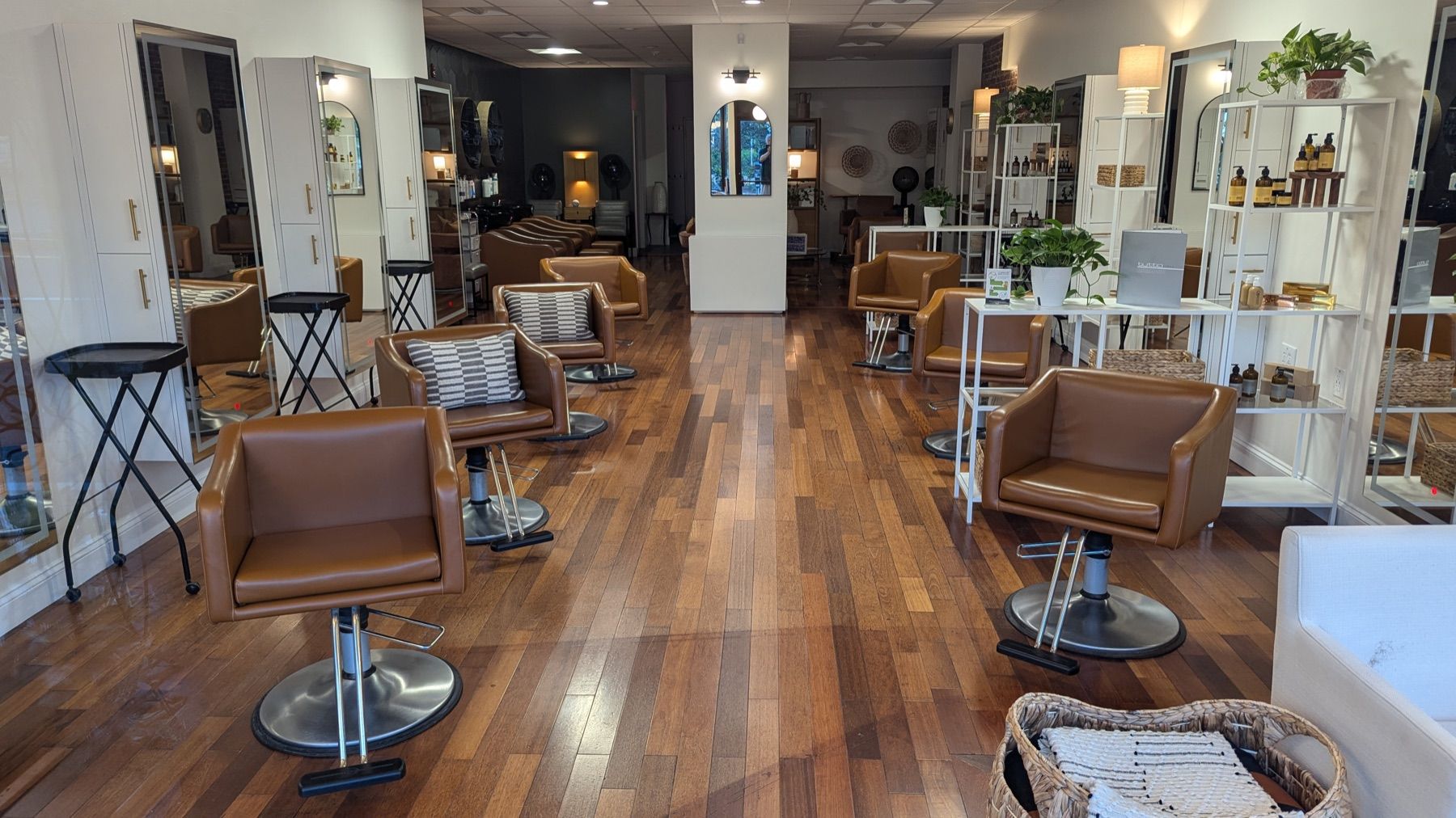 Lichte kapsalon met bruinleren stoelen, spiegels en een houten vloer